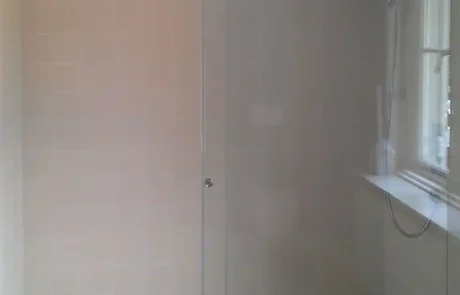 glaserei-wolff-duschwand Eine moderne begehbare Dusche mit Glasschiebetüren, beige gefliesten Wänden, einer Regendusche und einer dekorativen Bordüre entlang der Bodenfliesen.